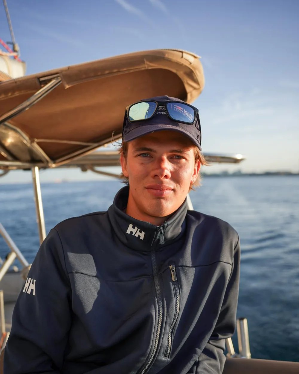 Retrato de Lorenz Moraes Deufel a bordo, con gorra y chaqueta náutica azul marino